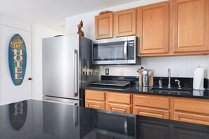 Eine moderne Küche mit Edelstahl-Kühlschrank, Mikrowelle und Holzschränken.
