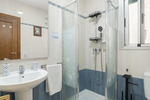 A bathroom with a glass-enclosed shower, a sink with two patterned soap dispensers, and a white towel hanging on a rack. - Central House with Private Solarium in Barbate, Costa de la Luz (Barbate)
