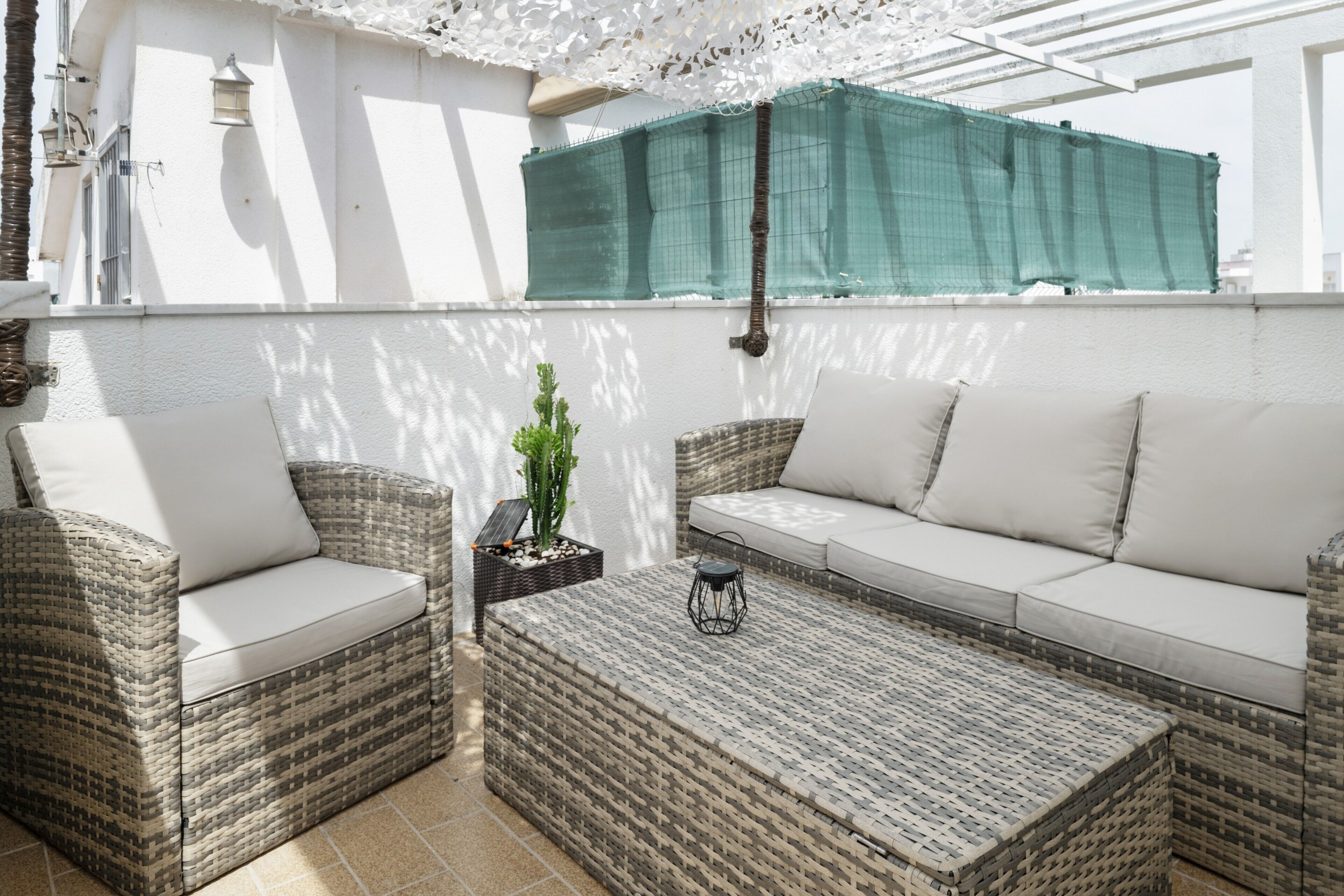 A patio with wicker furniture, a small table, and a potted plant.