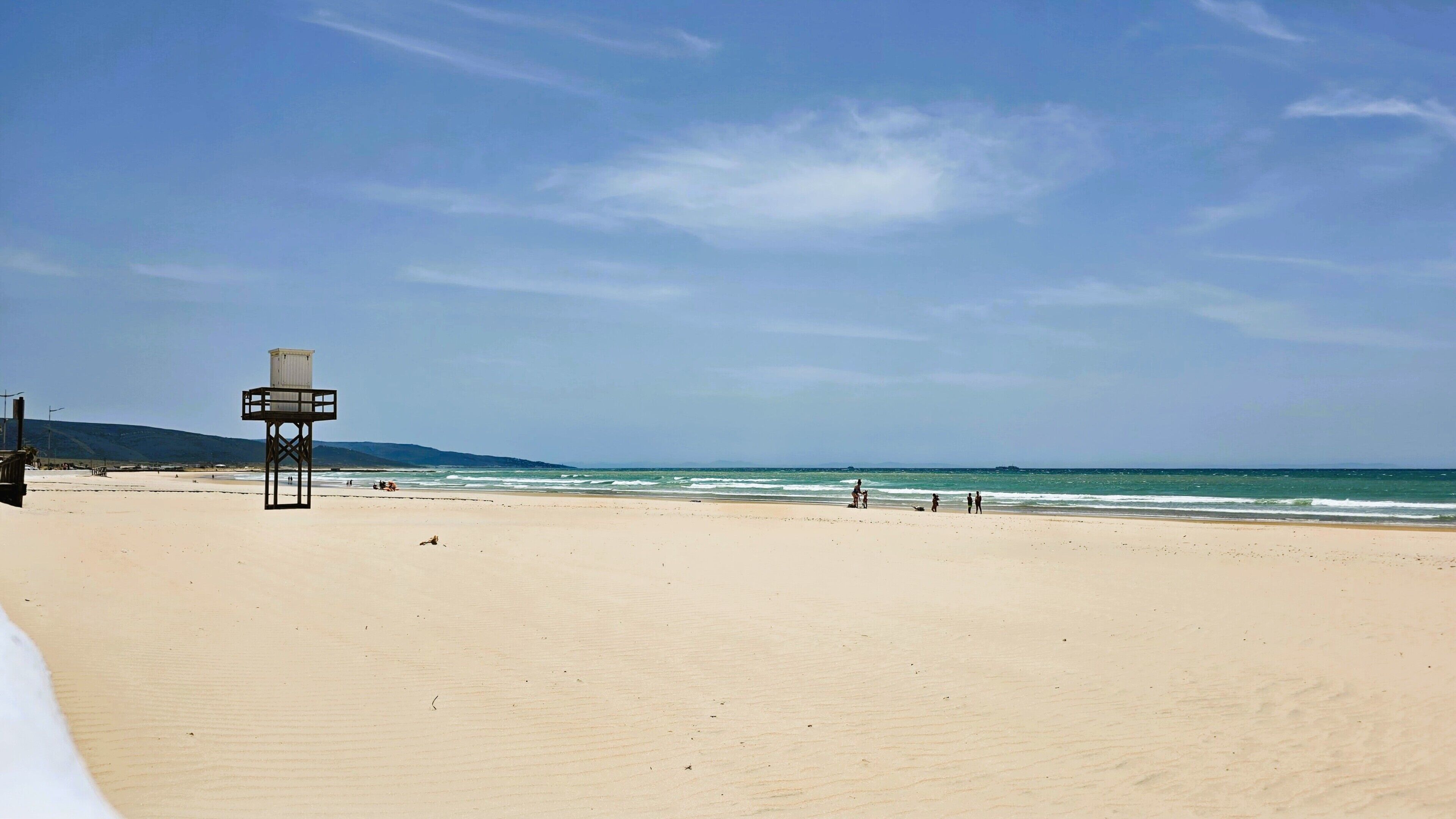 A beach with a lifeguard tower, sandy beach, and ocean view.