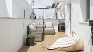 A sunlit patio with wicker furniture, a potted plant, and a striped bean bag. - Central House with Private Solarium in Barbate, Costa de la Luz (Barbate)