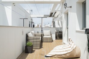 A sunlit patio with wicker furniture, a potted plant, and a striped bean bag. - Central Duplex with Private Solarium in Barbate (Barbate)