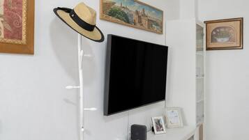 A room with a mounted flat-screen TV, a hat on a stand, and framed artwork on the walls.