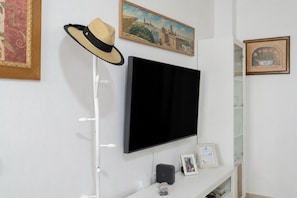 A room with a mounted flat-screen TV, a hat on a stand, and framed artwork on the walls. - Central House with Private Solarium in Barbate, Costa de la Luz (Barbate)