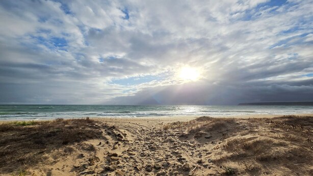 A beach with a sandy foreground, ocean waves, and a cloudy sky with sunlight breaking through. - Central House with Private Solarium in Barbate, Costa de la Luz (Barbate)