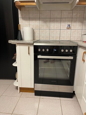 A kitchen with a built-in oven and stovetop, white cabinets, and a tiled backsplash. - One beautiful accommodation with good atmosphere & comforts!!! (Greece City)
