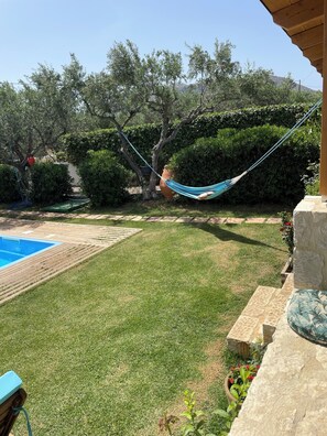 Ein Garten mit Pool, einer Hängematte und einer Steinmauer.