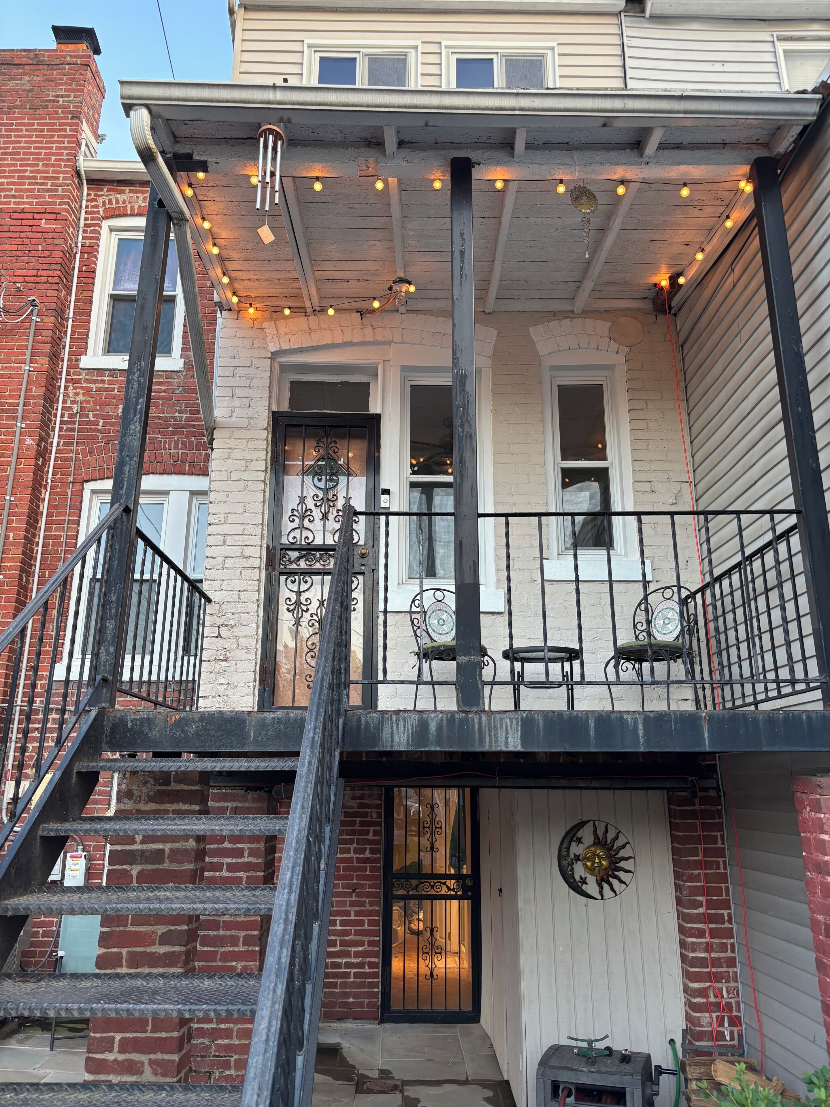 A two-story building with a balcony, a fire escape, and a decorative sun wall.