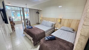 Ein Hotelzimmer mit zwei Betten, einem Fernseher, einem Schreibtisch und Blick ins Freie.