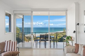 A balcony with a view of the ocean, a dining table, and a sofa. - 22 Dent Crescent - Spacious Coastal Retreat with Stunning Ocean Views (Port Macquarie)