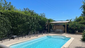 Une piscine rectangulaire dont le bord est recouvert de carreaux, entourée d’une terrasse en gravier.