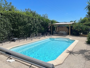 A rectangular swimming pool with a tiled edge, surrounded by a gravel patio.