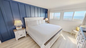 A bedroom with a large bed, two bedside tables, a nightstand, a chair, and a dresser. - Beach House 101c 2 Bedroom Condo (Miramar Beach)
