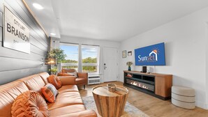 A modern living room with a leather sofa, a wooden coffee table, a fireplace, and a television. - Rc305a- The Landing Pad 2 Bedroom Condo (Branson)