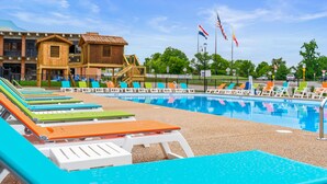A swimming pool with lounge chairs, a wooden building, and flags. - Rc305a- The Landing Pad 2 Bedroom Condo (Branson)