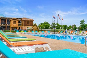 A swimming pool with lounge chairs, a wooden building, and flags. - Rc305a- The Landing Pad 2 Bedroom Condo (Branson)
