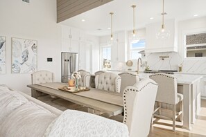A modern kitchen with white cabinetry, a central island, and pendant lighting. - Wave On Wave 4 Bedroom Home (Port Bolivar)