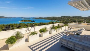 A rooftop terrace with a view of the sea, outdoor furniture, and potted plants. - Villa Sara Murter (Jezera)