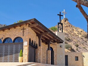 Igreja de pedra com cruz, janelas em arco e um campanário.