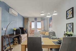 Un comedor con una mesa de madera, sillas grises y un televisor sobre un mueble de madera.