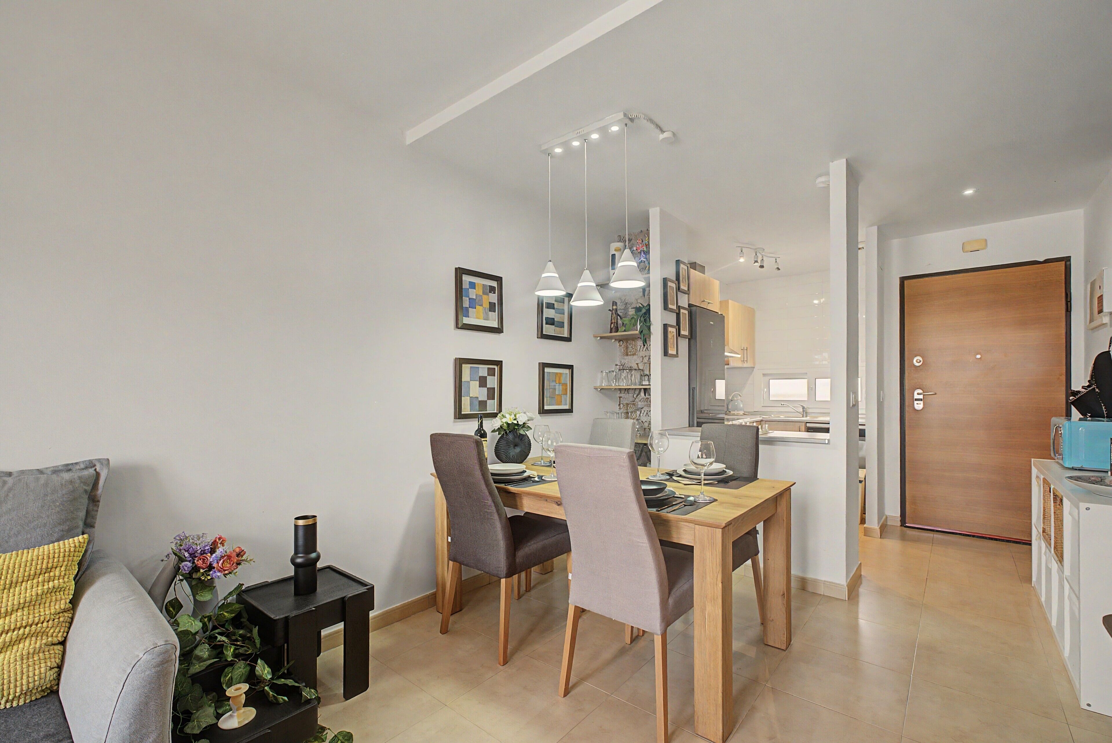 A modern dining area with a wooden table, chairs, and pendant lighting.