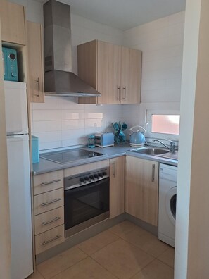 Una cocina compacta equipada con estufa, horno, microondas y lavadora.