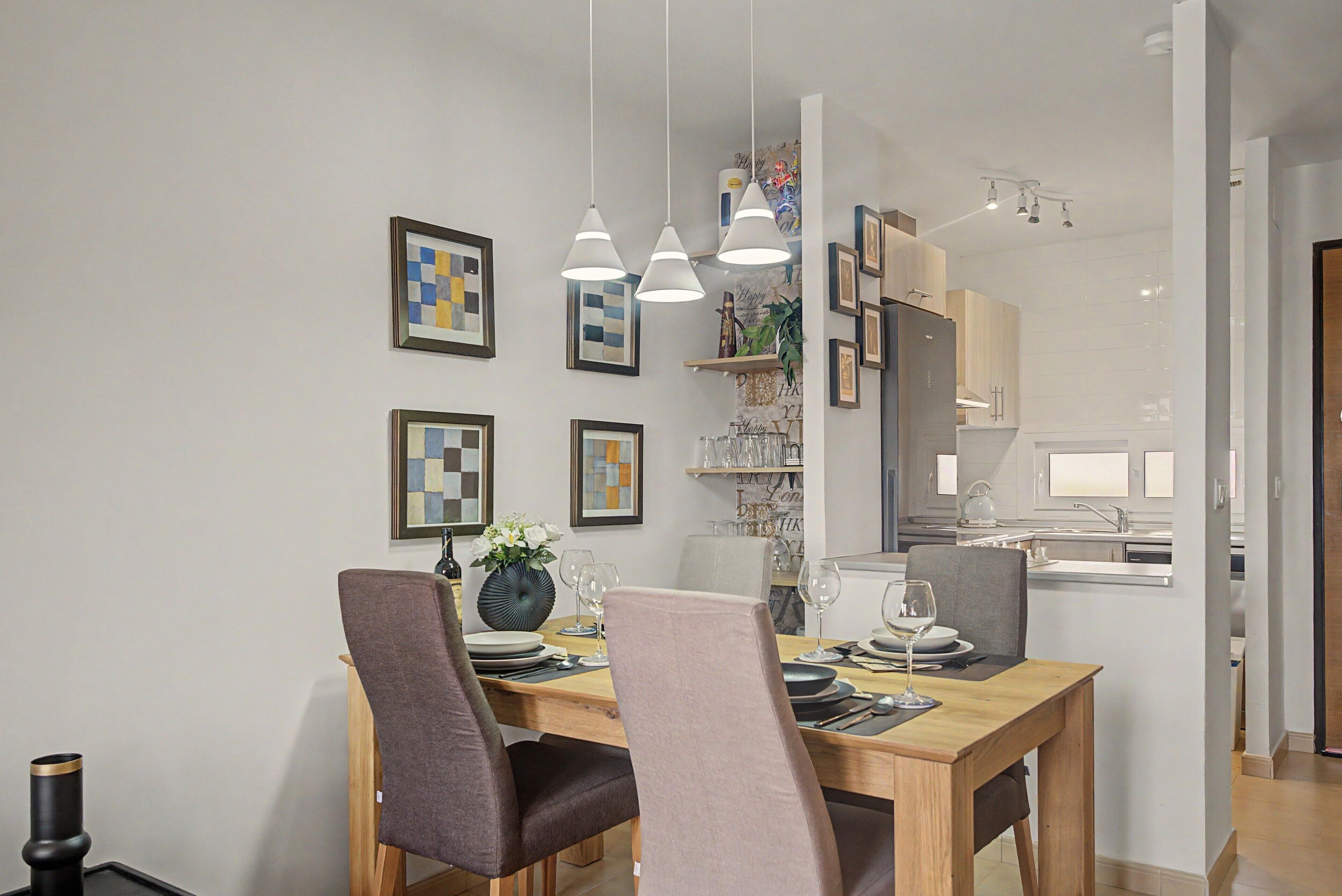 Comedor con mesa de madera, sillas y lámparas colgantes.