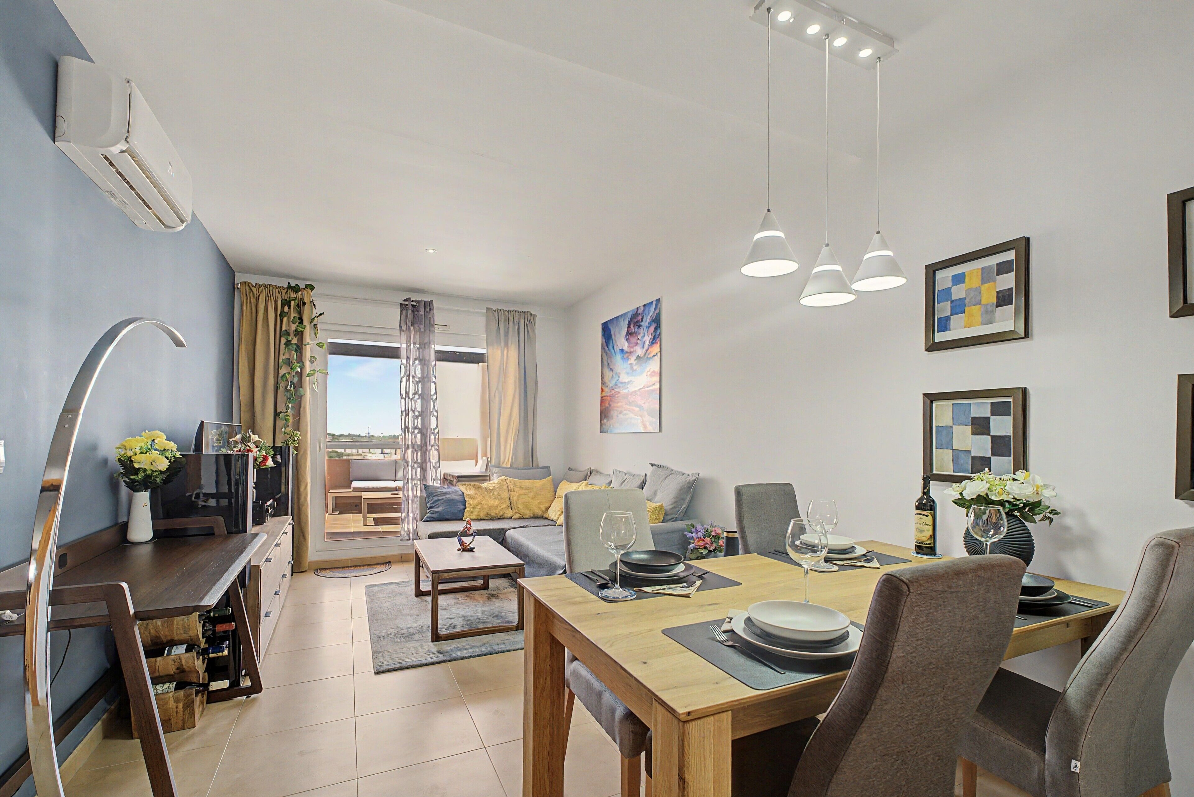 Een moderne woonkamer met een eethoek, een televisie en een groot raam.