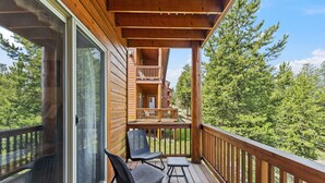 Eine Holzterrasse mit Glastür, zwei Stühlen und einem kleinen Tisch.