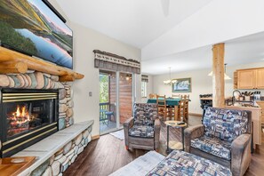 A cozy living room with a fireplace, comfortable seating, a dining area, and a kitchen. - Central Dillon Retreat | Ski, Hike, Explore (Dillon)