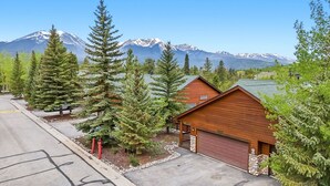 Eine Hütte mit Garage, umgeben von immergrünen Bäumen und Blick auf die Berge.