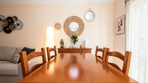 A dining area with a wooden table, chairs, a sofa, and decorative wall art. - Casa Manuel Vaz Near Tavira (Tavira)
