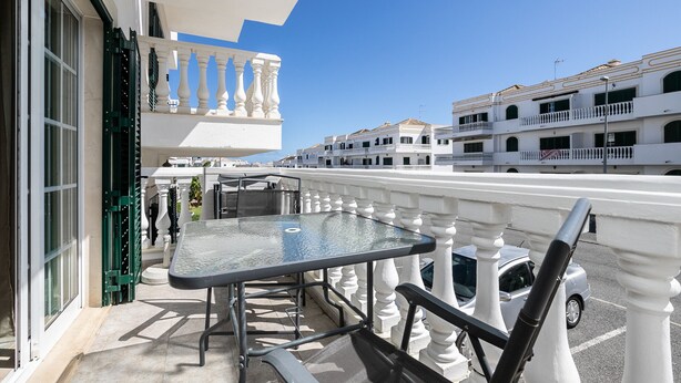 A balcony with a glass table and chairs, white balustrades, and a view of adjacent buildings. - Casa Manuel Vaz Near Tavira (Tavira)