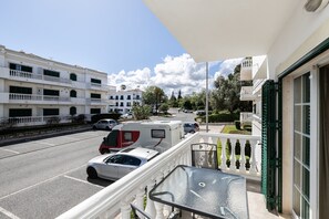 Un balcon donnant sur une rue, un camping-car garé et un immeuble doté de plusieurs balcons.