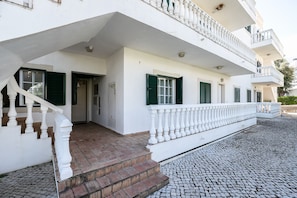 Un bâtiment blanc doté d’un balcon, d’un escalier et d’un sol pavé.