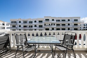 A rooftop terrace with a glass table and chairs, white balustrades, and a multi-story building in the background. - Casa Manuel Vaz Near Tavira (Tavira)