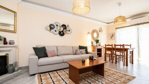 A living room with a sofa, coffee table, and dining area with chairs. - Casa Manuel Vaz Near Tavira (Tavira)