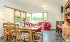 Un coin repas avec une table et des chaises en bois, un canapé rouge et une cheminée.