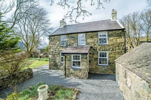 Una casa de piedra con un camino de grava y un jardín.