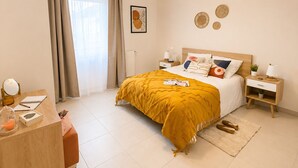 A hotel room with a bed, bedside tables, a desk, a mirror, and a window with curtains.
