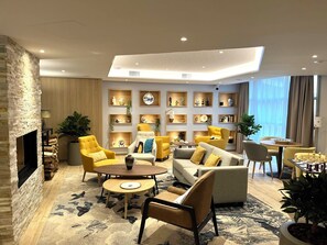 A modern living room with a fireplace, yellow armchairs, a sofa, and a chess table. - Zenao Appart'hôtels Limoges (Limoges)
