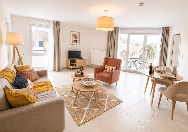A modern living room with a sofa, armchair, coffee table, and dining table.