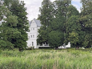 Ein großes Gebäude mit einem Turm, umgeben von üppiger Vegetation und Bäumen.