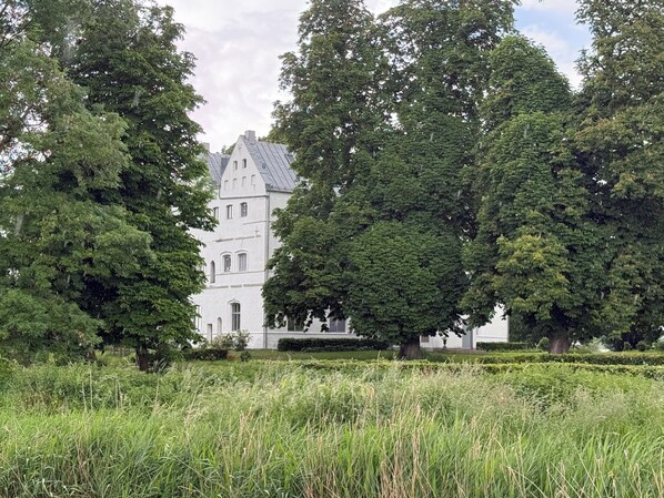 Ein großes Gebäude mit einem Turm, umgeben von üppiger Vegetation und Bäumen.