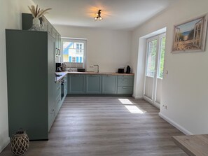 Eine Küche mit hellgrünen Schränken, einer Holz Arbeitsplatte, einer Spüle und einem Fenster.