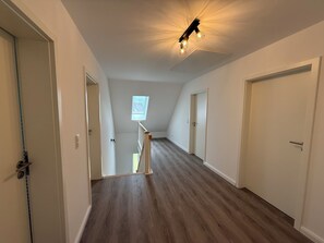 Ein Korridor mit Holzboden, weißen Wänden und einem Oberlicht.