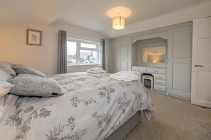 A bedroom with a bed, a dresser, a mirror, and a window. - Hirdre -  a self catering cottage that sleeps 6 guests in 4 bedrooms (Pwllheli)