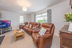 Ein Wohnzimmer mit einer Ledersofa, einem Fernseher und einem Couchtisch aus Holz.