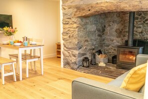Una sala acogedora con chimenea de piedra, suelo de madera y una mesa de comedor con sillas.