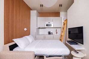 A hotel room with a bed, a TV, a microwave, and a kitchenette. - Montmartre-Mobility lease-Studio-2 persons-Renovated (Paris)